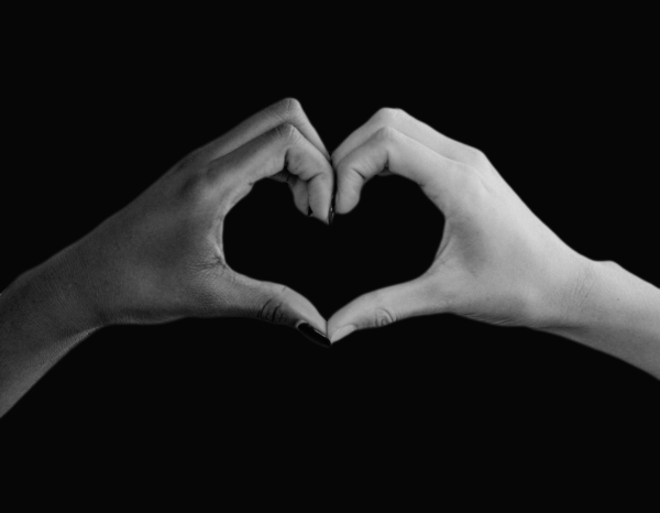 Hands held together to make a heart shape. One black hand. One white hand.