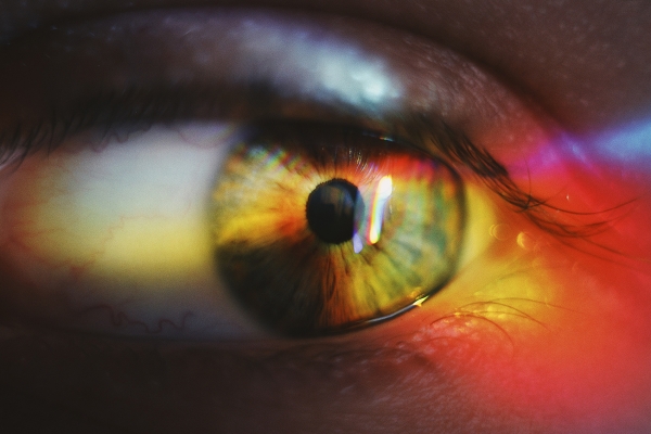 Close up of a person's eye reflecting rainbow colors