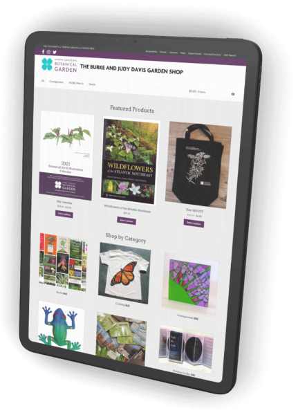 An iPad with the NC Botanical Garden shop website on the screen. Large thumbnail images of shop items and purchase buttons appear on the screen.