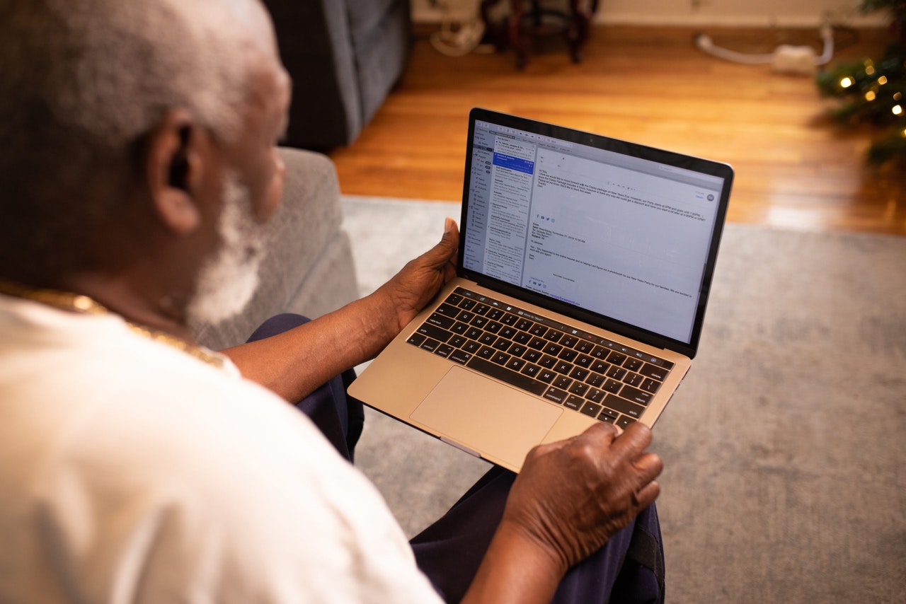 An old black man using an Apple laptop