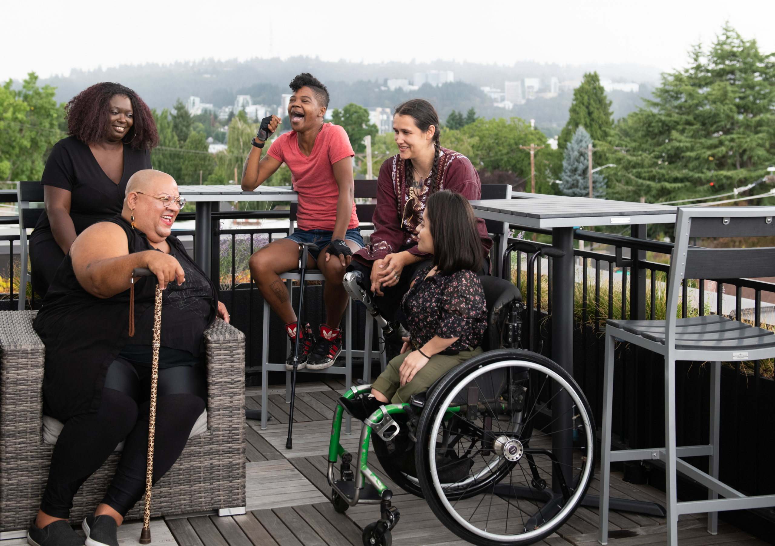 A group of disabled black women and latinas laughing on a patio